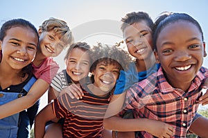 Six pre-teen friends piggybacking in a park, close up portrait