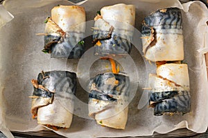 Six rolls of mackerel with vegetables stacked in a bowl for baking.