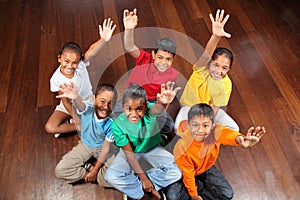 Six school children sitting in classroom hands up