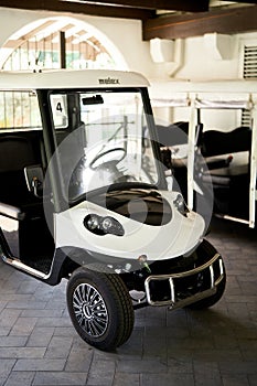 Six-seater golf cart stands in a covered parking lot on a tile