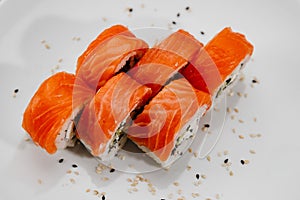 Six servings of sushi with salmon and cucumber on a white plate