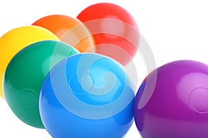 Six shiny coloured plastic toy balls isolated