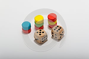 Six-sided dice and circular wooden chips of different colors, red, green, blue, yellow for use in board games such as parcheesi