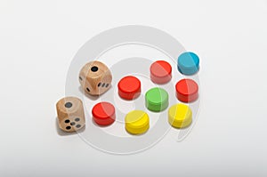 Six-sided dice and circular wooden chips of different colors, red, green, blue, yellow for use in board games such as parcheesi