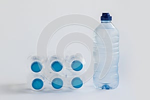 Six small pet bottles of natural spring water lay near one liter of water