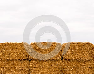 Six stacked yellow hay bales on overcast sky