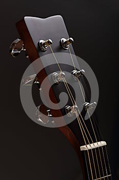 Six-stringed acoustic guitar head with tuning pegs close-up
