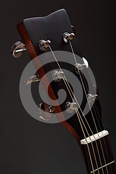 Six-stringed wooden acoustic guitar head with tuning pegs