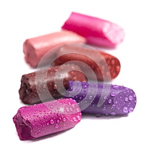Six Tubes of Lipstick Broken and Isolated on a White Background Covered in Water