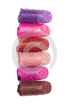 Six Tubes of Lipstick Broken and Isolated on a White Background Covered in Water