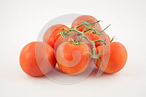 Six unpeeled, fresh, red tomatoes with green tails on white back