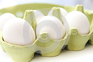 Six white chicken eggs in a open green package