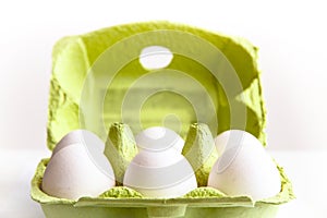 Six white eggs in a open green package