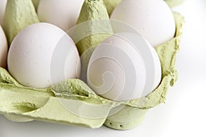 Six white eggs in a open green package, viewed from the top