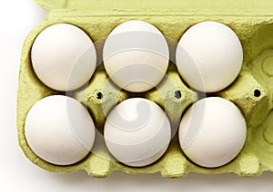 Six white eggs in a open green package, viewed from the top