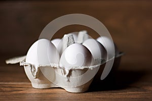 Six white eggs package on a brown wood
