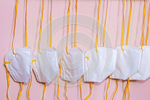 Six white medical N95 mask with yellow strings hanging side of wall to protect against corona viruscovid19