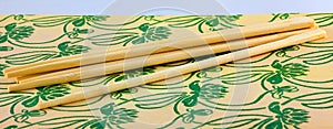 Six wooden chopsticks on a leaf and flower surface.