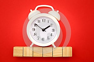 Six wooden cubes with space for text and alarm clock on red background. Time is money concept. Time-limit. Business