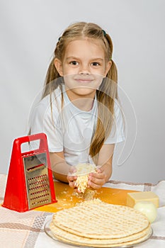 Six-year girl sitting at kitchen table in front of her are vegetables, base and other ingredients