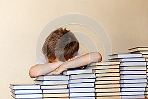 Six-year-old boy sitting at the table, his hands and head on the book
