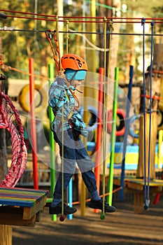 Six year old boy surmounting obstacle course in the rope park photo