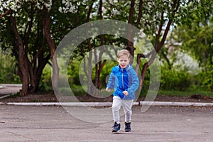 Six-year-old Caucasian boy in a blue windbreaker and gray pants running in the Park