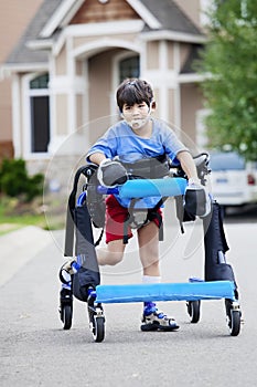 Six year old boy walking in walker down the street