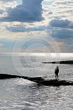 A six year old unrecognisable boy alone walking along a jetty in the sea