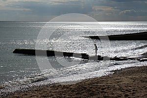 A six year old unrecognisable boy walking along a jetty in the sea