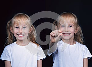 Six year smiling happy girl holding a first fallen tooth and looking at him.