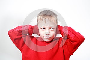 Six-years old boy in red hoodie closing ears with his hands on grey background. Autism concept