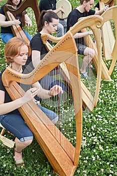 Six young musicians perform playing harps outdoors photo
