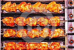Sixteen chickens roasting on, spits of a comercial roasting oven photo