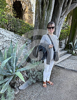 Sixty-five year-old female Korean tourist in the Garden of the villa Cipressi in Varenna.