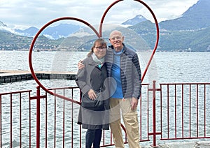 Sixty-five year-old Korean tourist and her seventy-six year old Caucasian husband posing in a a heart beside Lake Como. photo