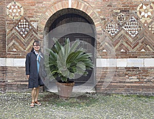 Sixty-five year old Korean tourist beside a Sago palm in the courtyard of Pilate in the Basilica of Saint Stephen.