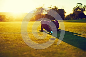 Sizing it up before he sinks it. a young man eyeing up the putt during a round of golf.