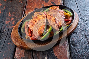 Sizzling chicken fillet with vegetables on rustic wooden table