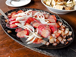 Sizzling Hotdog and onions, a popular Filipino appetizers or pulutan served in a restaurant or bar photo