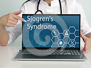 Sjogren`s Syndrome text in list. Podiatrist looking for something at laptop photo