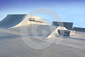 Skate park generic concrete ramps outside with blue sky photo