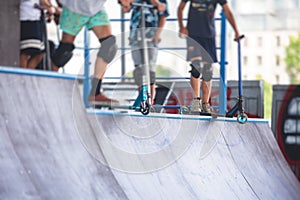 Skate park view with kids on a kick scooter doing tricks and stunts, boys in a skate park riding bmx bike and skate, playing and
