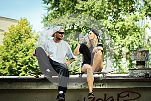 Skateboard boy and girl sitting and drinking water