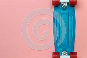 Skateboard cruiser with blue deck and red wheels on pink background, top view with copy-space. Concept of sport lifestyle, culture