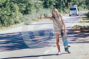 Skateboard girl hitchhiking and stopping car with thumbs up gesture at countryside road