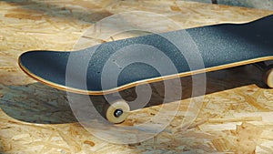 Skateboard with white wheels on a wooden background in a skatepark
