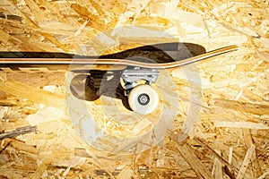 Skateboard with white wheels on a wooden background in a skatepark