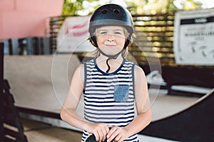 Skateboarder boy in helmet posing in skate park. Kid boy with skateboard. Childhood, leasure, lifestyle concept. Portrait stylish