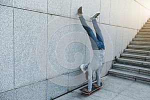 Skateboarder doing a handstand on skateboard against wall